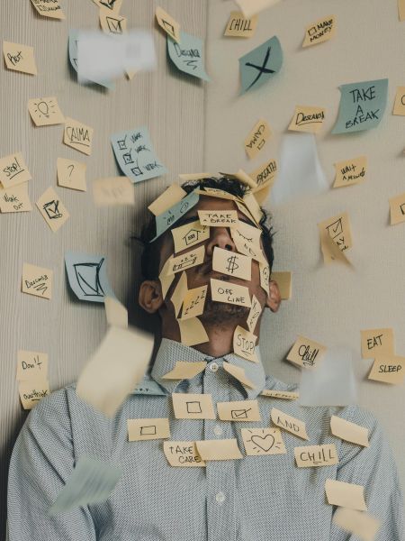 Photo d'un homme épuisé avec le visage et les murs autour recouverts de post-its