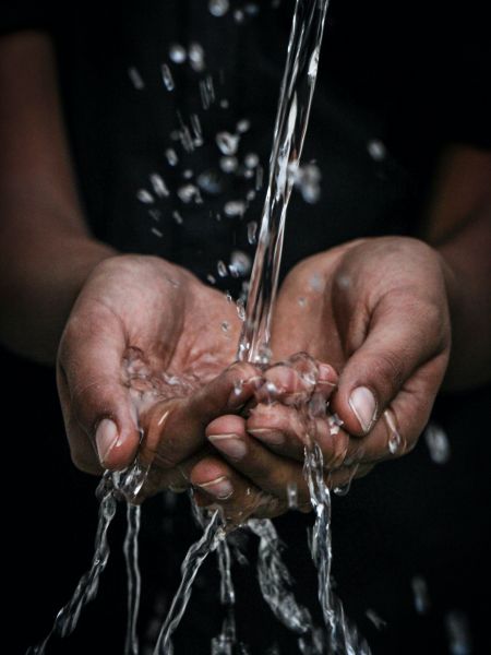 Deux mains reçoivent de l'eau coulant d'une source hors champ