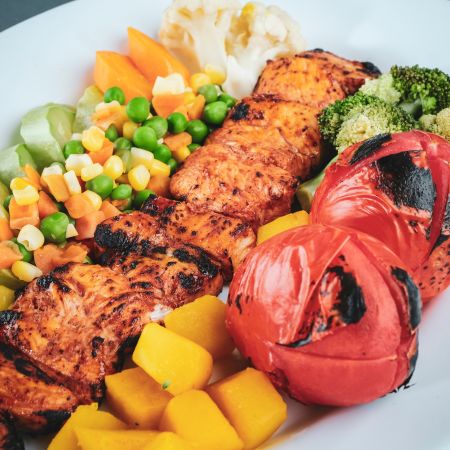 Un plat constitué de viande, de crudités et de légumes grillés au barbecue